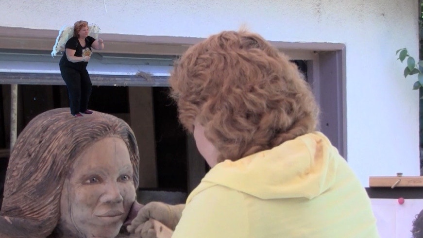 Casey McCaughn working on the life size chainsaw woodcarving of Oprah Winfrey and an angel